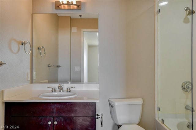 full bathroom featuring toilet, combined bath / shower with glass door, and vanity