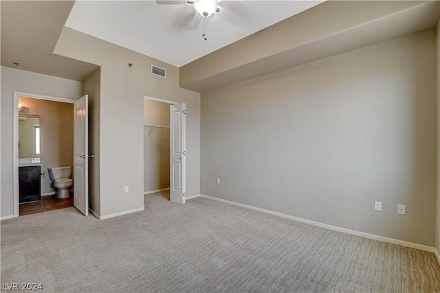 unfurnished bedroom with ensuite bathroom, light colored carpet, visible vents, baseboards, and a closet