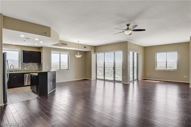 interior space with a ceiling fan, visible vents, dark wood finished floors, and baseboards