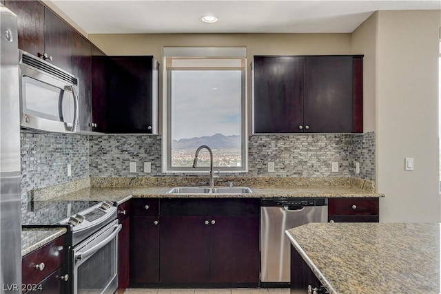 kitchen featuring a mountain view, a sink, appliances with stainless steel finishes, light stone countertops, and tasteful backsplash