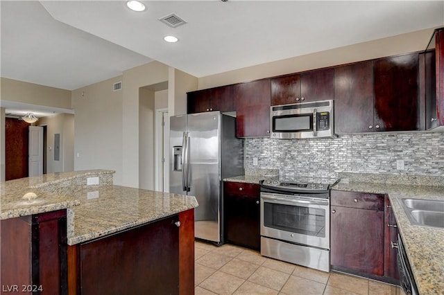 kitchen with a kitchen island, appliances with stainless steel finishes, backsplash, light tile patterned floors, and light stone counters