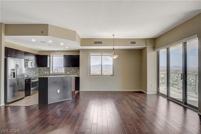 kitchen featuring dark wood-style floors, tasteful backsplash, appliances with stainless steel finishes, dark brown cabinetry, and a sink