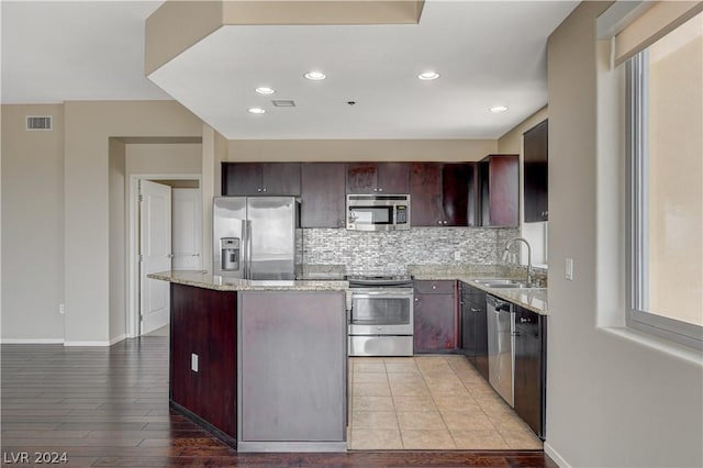 kitchen featuring visible vents, a center island, light stone countertops, stainless steel appliances, and a sink