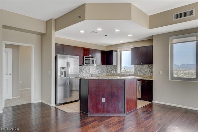 kitchen with stainless steel appliances, a center island, visible vents, and dark wood finished floors