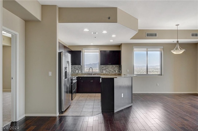 kitchen with tasteful backsplash, appliances with stainless steel finishes, hanging light fixtures, dark brown cabinets, and a sink