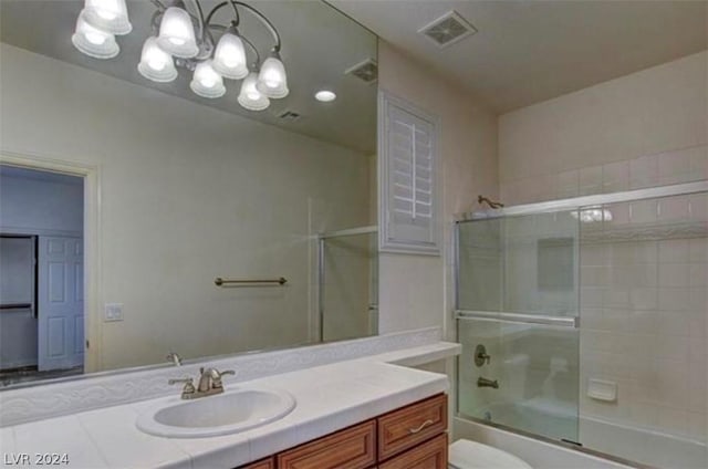 full bathroom featuring shower / bath combination with glass door, vanity, an inviting chandelier, and toilet