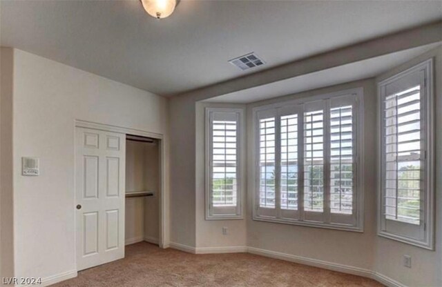 unfurnished bedroom featuring light carpet and a closet