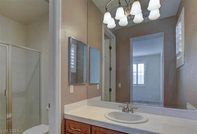 bathroom featuring vanity, toilet, walk in shower, and an inviting chandelier