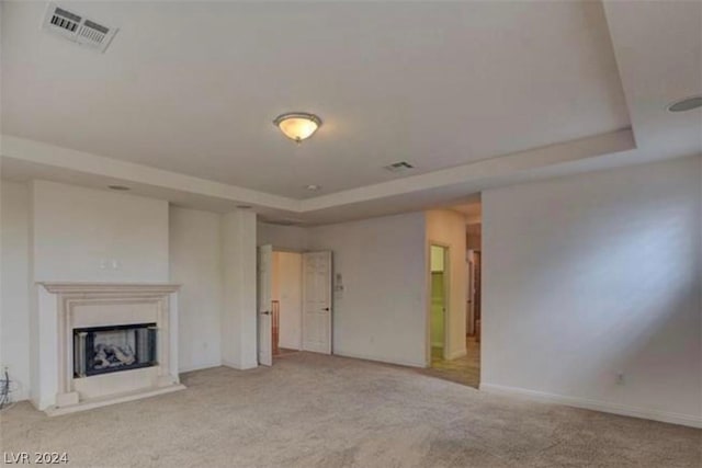 unfurnished living room with a tray ceiling and light colored carpet