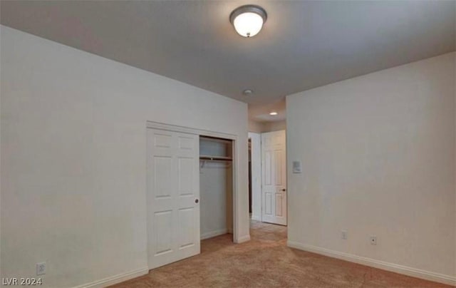 unfurnished bedroom featuring a closet and light colored carpet