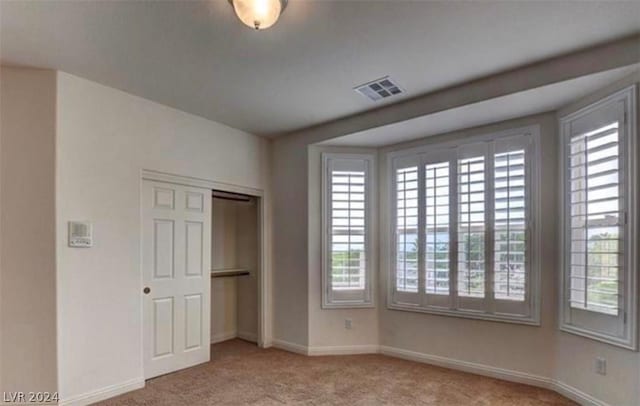 unfurnished bedroom with light carpet and a closet