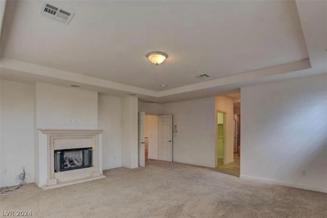 unfurnished living room with a tray ceiling and light colored carpet