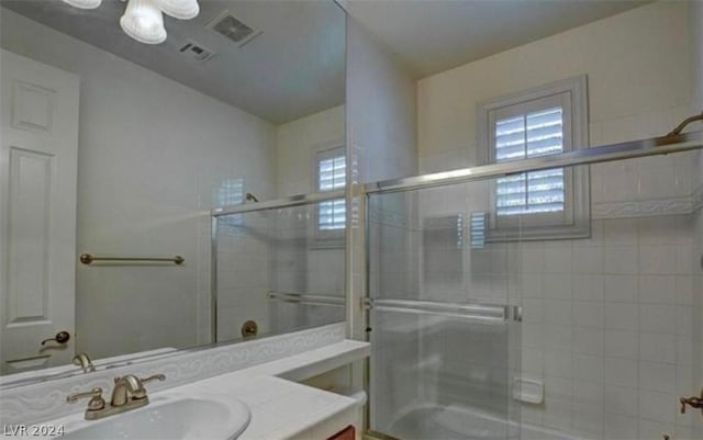 bathroom with vanity and shower / bath combination with glass door