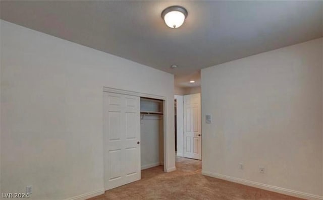 unfurnished bedroom with light carpet and a closet