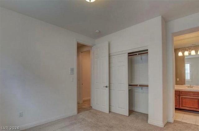 unfurnished bedroom with light colored carpet, ensuite bath, a closet, and sink