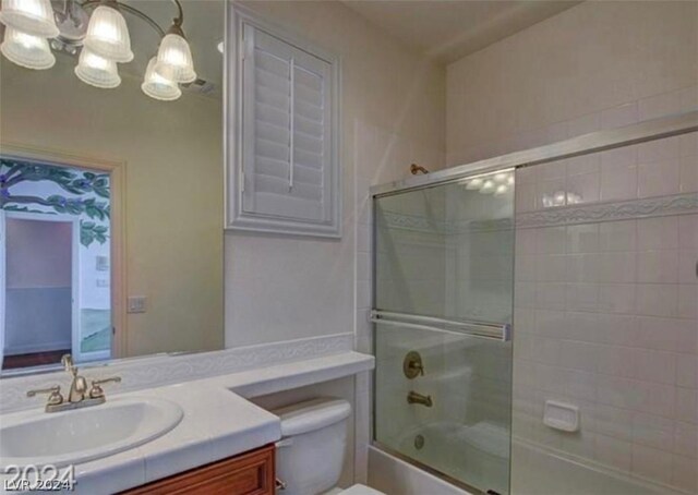 full bathroom featuring vanity, toilet, and bath / shower combo with glass door