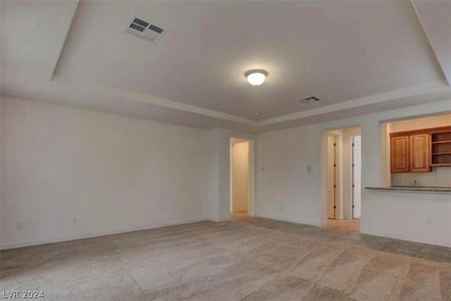 unfurnished living room with a tray ceiling and light colored carpet