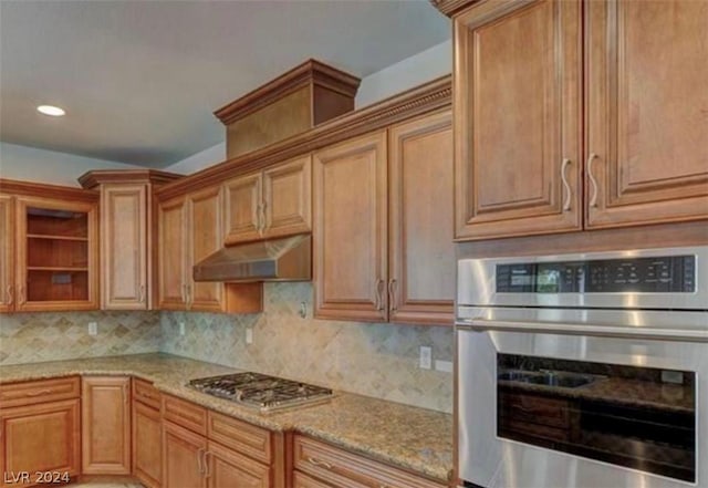 kitchen featuring light stone counters, backsplash, and appliances with stainless steel finishes