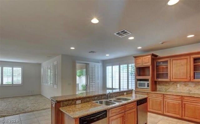 kitchen with backsplash, a kitchen island with sink, dishwasher, and sink