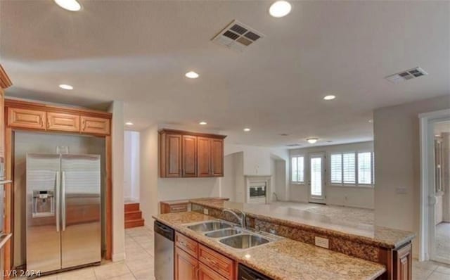 kitchen featuring sink, light stone countertops, stainless steel appliances, and light tile patterned floors