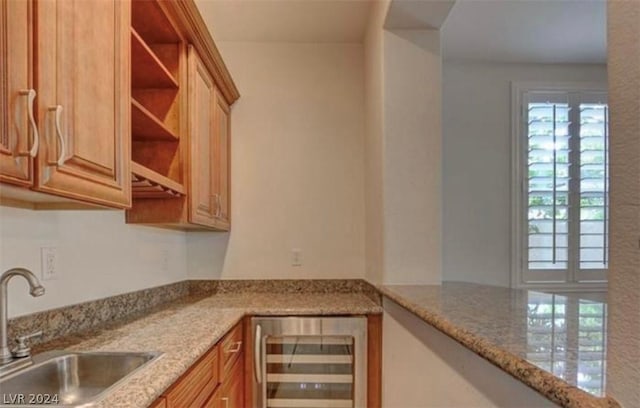 kitchen featuring light stone counters, wine cooler, and sink