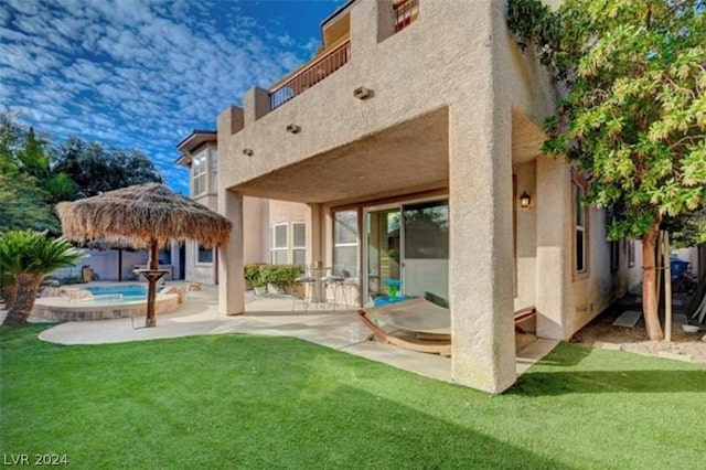 rear view of property with a balcony, a yard, and a patio