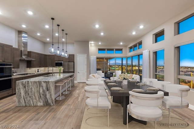 dining room with sink, light hardwood / wood-style flooring, and a towering ceiling