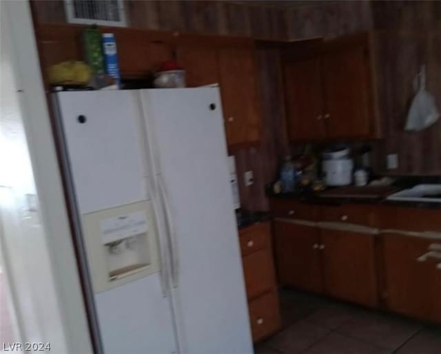 kitchen featuring dark tile patterned flooring and white refrigerator with ice dispenser