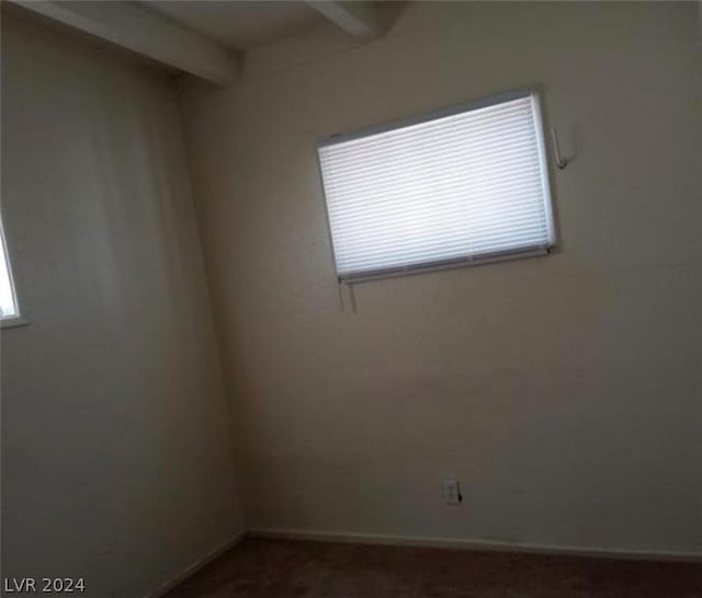 unfurnished room with beam ceiling