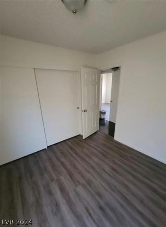 unfurnished bedroom with a closet and dark wood-type flooring