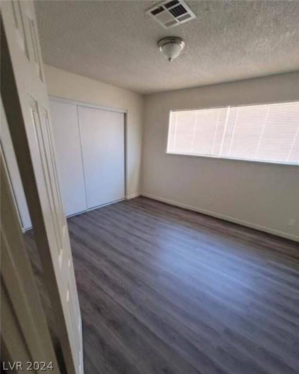 unfurnished bedroom featuring dark hardwood / wood-style flooring and a closet