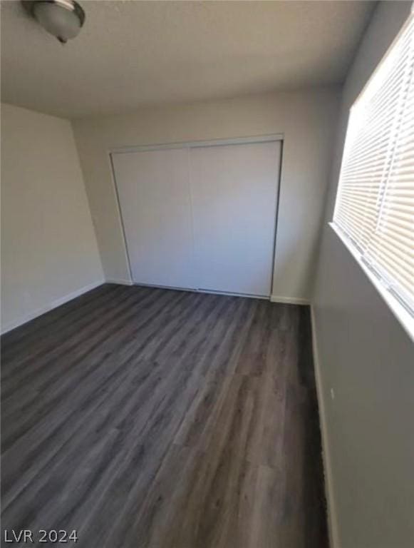 unfurnished bedroom featuring dark wood-type flooring and a closet