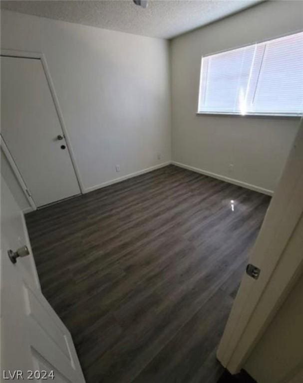 spare room with a textured ceiling and dark wood-type flooring