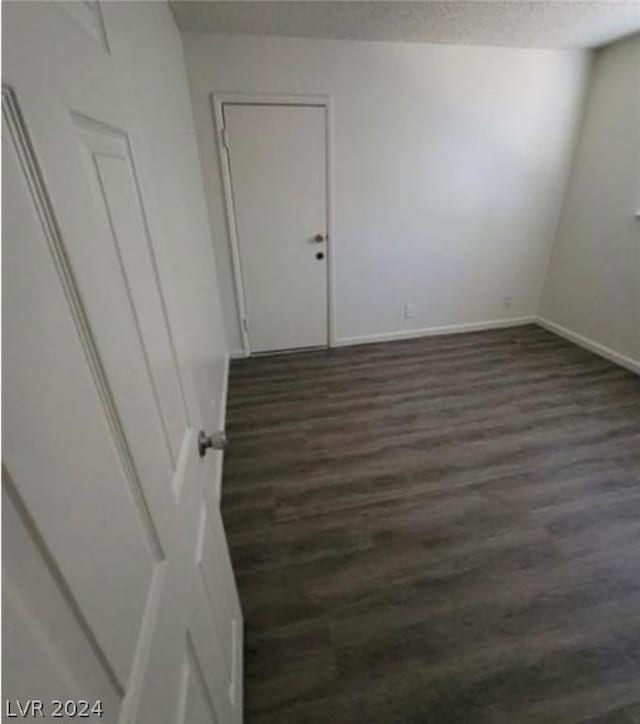 empty room featuring a textured ceiling and dark hardwood / wood-style floors