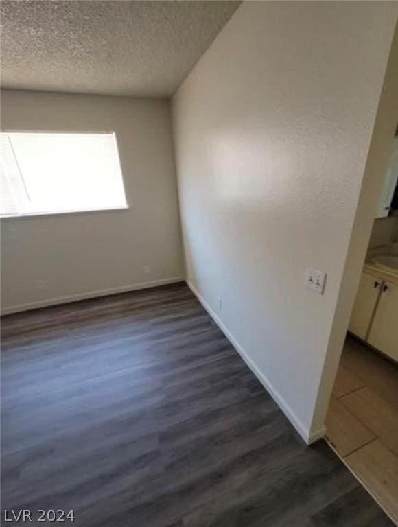 unfurnished room featuring a textured ceiling and dark hardwood / wood-style floors