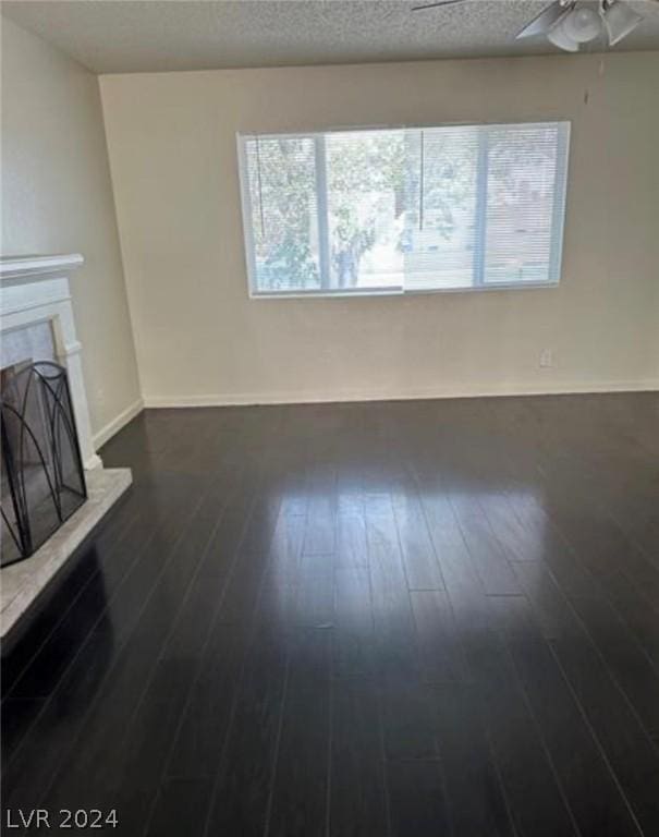 unfurnished living room featuring a textured ceiling, ceiling fan, and dark hardwood / wood-style floors