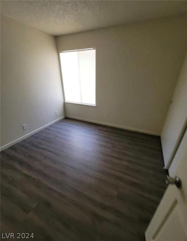 spare room featuring dark hardwood / wood-style flooring and a textured ceiling