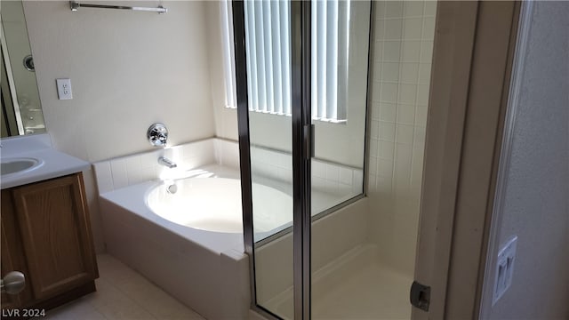 bathroom featuring tile flooring, a relaxing tiled bath, and large vanity