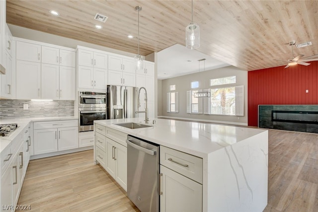 kitchen featuring pendant lighting, backsplash, a center island with sink, light hardwood / wood-style flooring, and stainless steel appliances