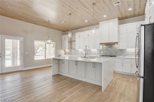 kitchen featuring stainless steel fridge, light wood-type flooring, sink, a center island with sink, and white cabinets