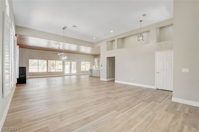 unfurnished living room featuring a high ceiling, light hardwood / wood-style floors, and ceiling fan