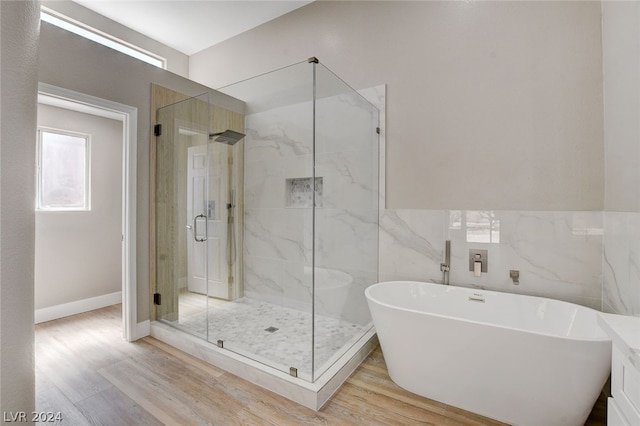 bathroom with hardwood / wood-style floors, tile walls, and plus walk in shower