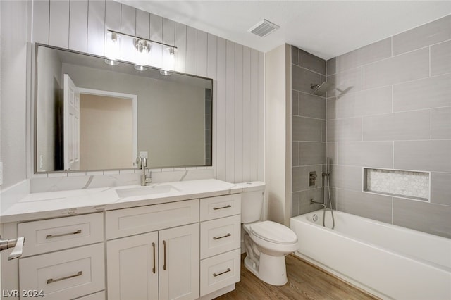 full bathroom with vanity, wood-type flooring, tiled shower / bath combo, and toilet