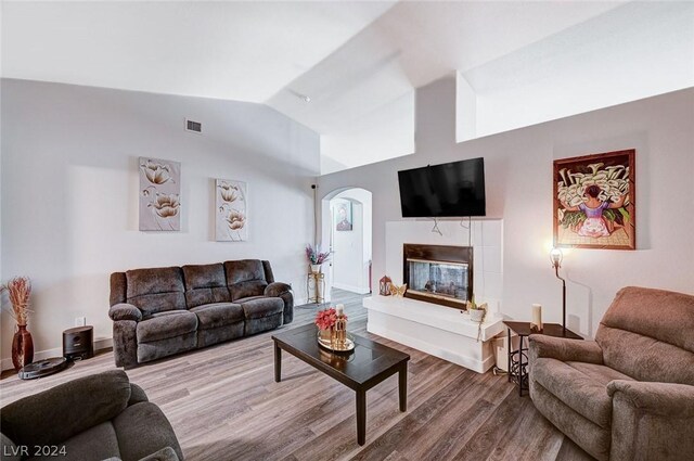 living room with a premium fireplace, lofted ceiling, and hardwood / wood-style floors