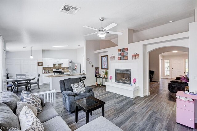 living room featuring ceiling fan, dark hardwood / wood-style floors, and vaulted ceiling