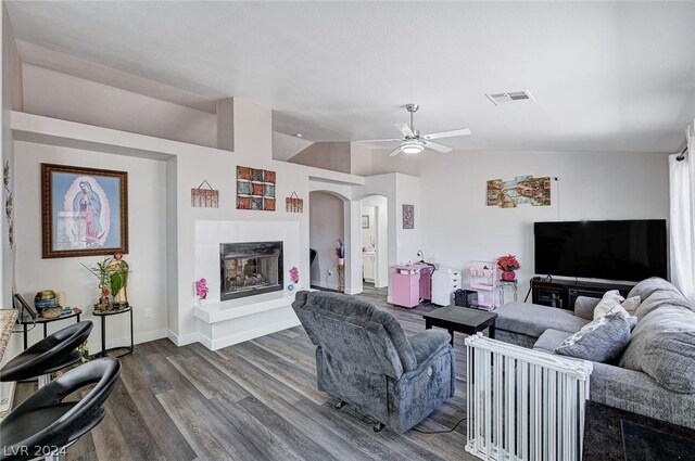 living room with hardwood / wood-style flooring, ceiling fan, lofted ceiling, and a fireplace