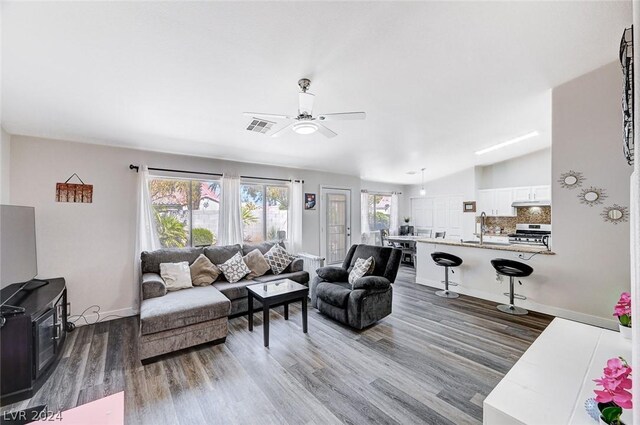 living room with lofted ceiling, sink, light hardwood / wood-style floors, and ceiling fan