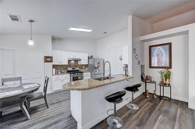 kitchen with sink, kitchen peninsula, pendant lighting, stainless steel appliances, and white cabinets