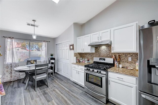 kitchen featuring stone counters, appliances with stainless steel finishes, lofted ceiling, white cabinets, and backsplash