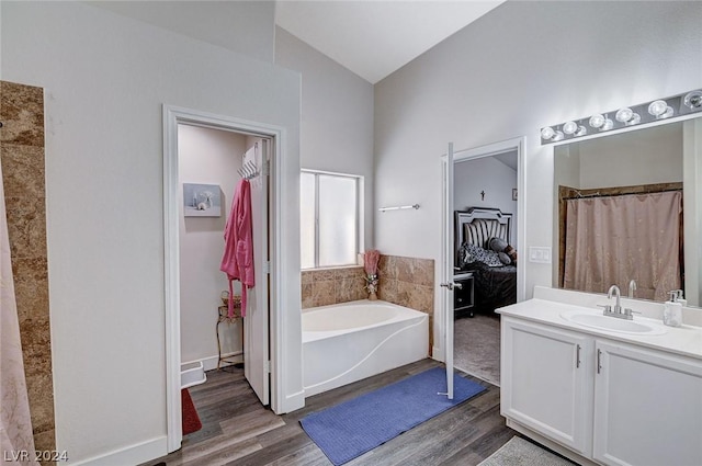 bathroom featuring vanity, vaulted ceiling, hardwood / wood-style floors, and a bathtub